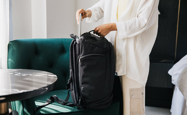 Person putting a laptop in the laptop compartment of the Techonaut 30. The bag is standing upright on a chair.